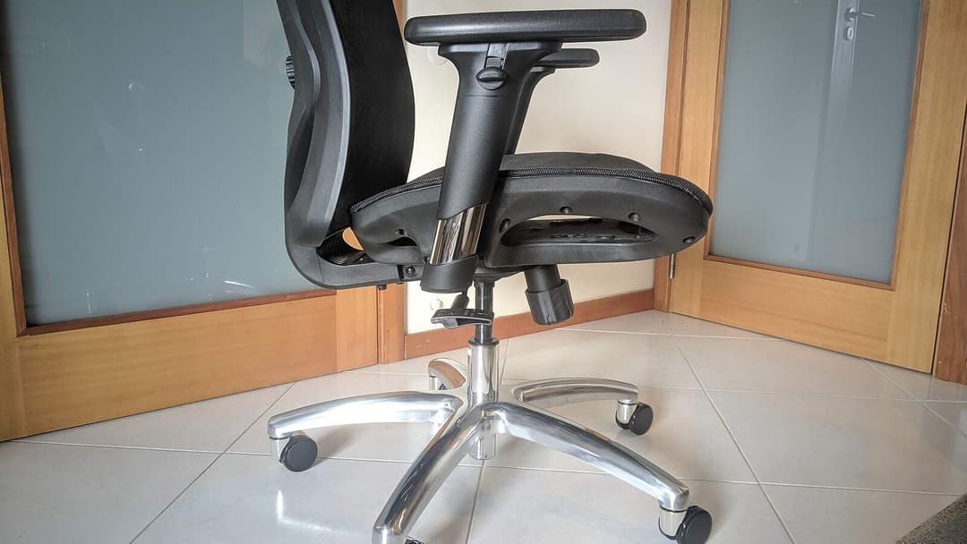 Side view of a black mesh office chair showing a padded armrest, the chrome gas-lift column and a polished five-star base on castors.