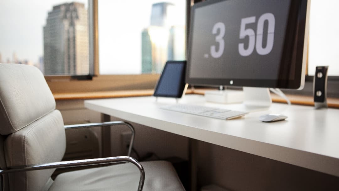 A close view of a white desk surface by a window with a city view, holding a large monitor, a tablet on a stand, a keyboard and a mouse, with a white leather office chair alongside.