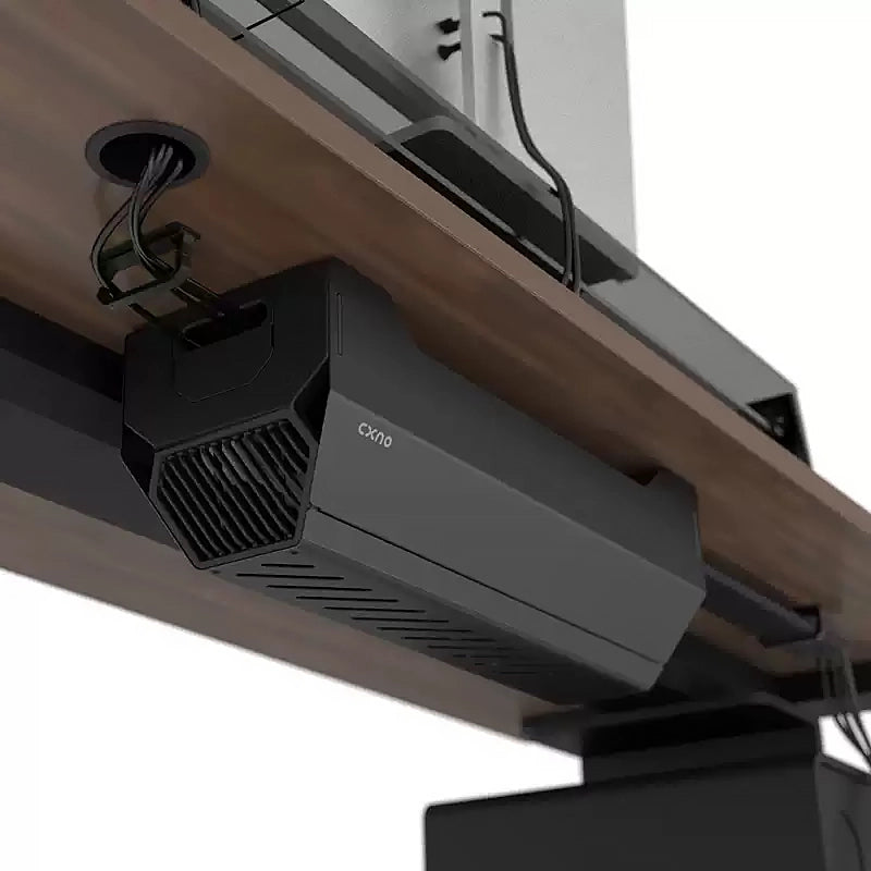 Under-desk cable management box installed on a wooden height-adjustable desk with cables routed through grommet